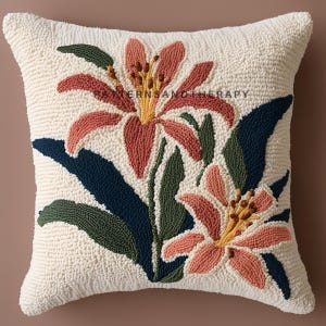 Può includere: Cuscino quadrato color crema con un design floreale. Il design presenta due grandi gigli nei toni del corallo, giallo e marrone, con foglie verdi e blu navy. Il testo "PATTERNSANDTHERAPY" è visibile sul cuscino. Accessorio decorativo.