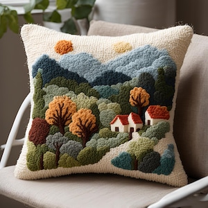 Può includere: Un cuscino bianco con una scena di paesaggio ricamata colorata. La scena presenta una catena montuosa, alberi, case e un sole. Il cuscino è perfetto per aggiungere un tocco di natura a qualsiasi stanza.