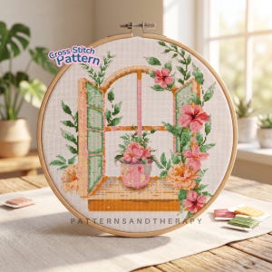 May include: A cross-stitch pattern in a wooden hoop features a window scene with pink flowers and green foliage. The text "Cross Stitch Pattern" and "PATTERNSANDTHERAPY" are visible. The design includes a pink flower pot on the windowsill.
