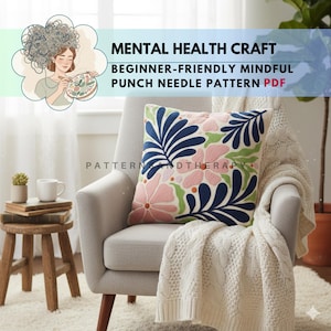 Könnte beinhalten: Ein dekoratives Kissen mit einem floralen Design in Rosa, Blau und Grün liegt auf einem grauen Sessel. Das Kissen hat gestickte Blumen und Blätter. Das Bild zeigt auch einen kleinen Holzschemel, eine weiße Decke und den Text "MENTAL HEALTH CRAFT".