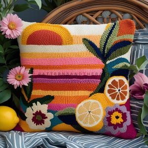Peut inclure: Un coussin décoratif carré et coloré avec un motif de coucher de soleil et des accents de citron et de fleurs. Le coussin présente un fond blanc avec des rayures horizontales dans les tons orange, rose et violet. Le motif comprend un soleil jaune, des citrons et des fleurs.