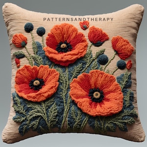 May include: A beige cushion with an embroidered design of red poppies and green leaves. The cushion has the text "PATTERNSANDTHERAPY" embroidered in the top centre.