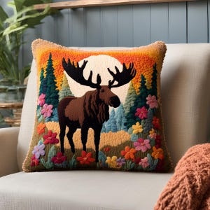 Peut inclure: Un coussin décoratif avec un motif brodé coloré d'un élan debout dans une forêt avec des fleurs et une pleine lune en arrière-plan.