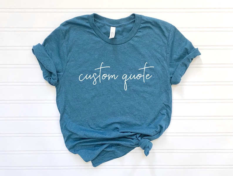 K&ouml;nnte beinhalten: Ein blaues T-Shirt mit dem Text "custom quote" in wei&szlig;en Buchstaben.