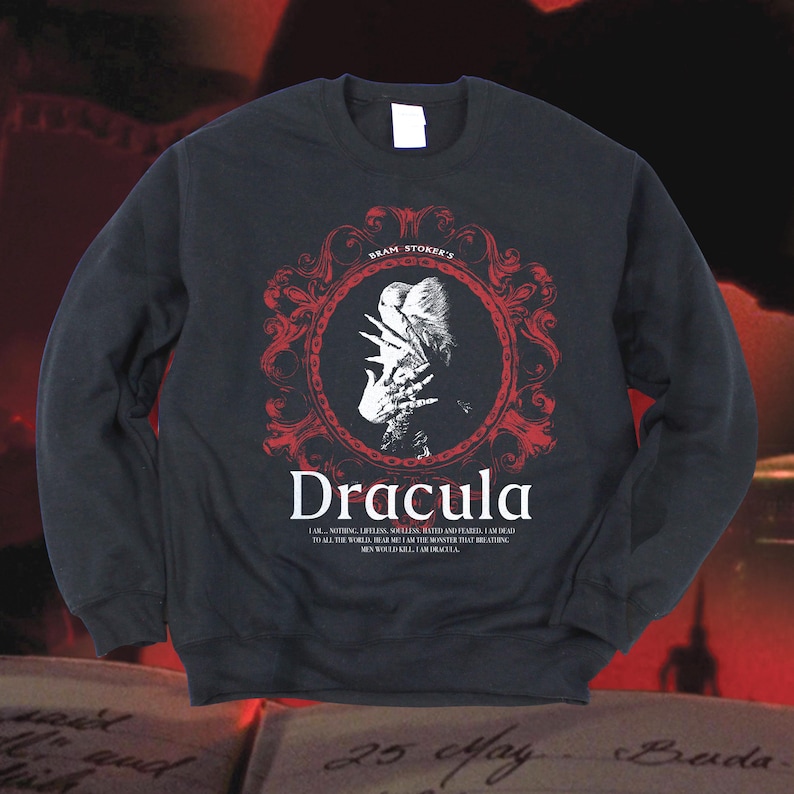 May include: Black sweatshirt featuring a red and white graphic of Dracula. The design includes the text "Bram Stoker's Dracula" and a quote from the novel. The sweatshirt is a crew neck style.