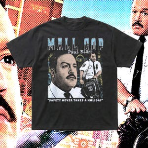 Puede incluir: Una camiseta negra de manga corta con un estampado gráfico de Paul Blart de la película Mall Cop. El diseño incluye el texto MALL COP, Paul Blart y la cita SAFETY NEVER TAKES A HOLIDAY, con un retrato y una imagen de cuerpo completo.