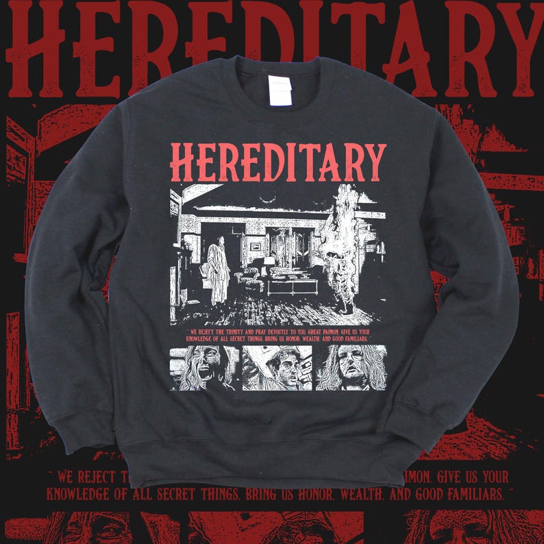 K&ouml;nnte beinhalten: Schwarzes Sweatshirt mit rotem Schriftzug "HEREDITARY". Die Vorderseite zeigt eine Schwarz-Wei&szlig;-Illustration eines Hausinneren und Gesichter. Der Text unten lautet "WE REJECT THE TRINITY..." und "SIMON GIVE US YOUR..."