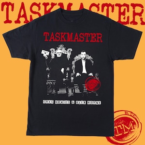 Może przedstawiać: Czarny T-shirt z białym nadrukiem przedstawiającym dwie osoby siedzące na tronach. Tekst "TASKMASTER" znajduje się u góry nadruku, a tekst "GREG DAVIES & ALEX HORNE" u dołu. Na nadruku znajduje się czerwona pieczęć z literami "TM".