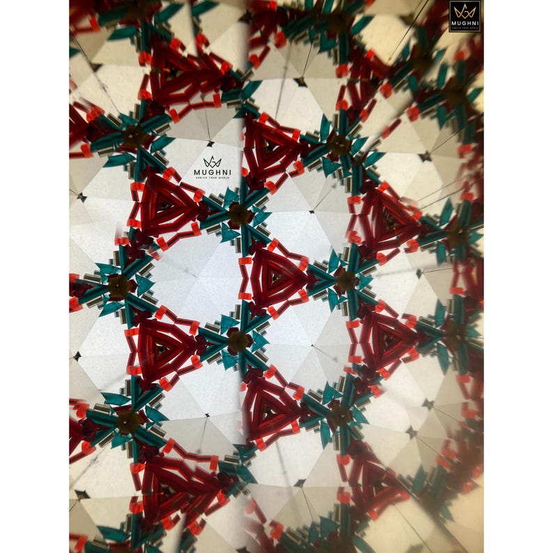 May include: Abstract kaleidoscope design with a repeating geometric pattern in red, teal, and white. The image features the brand name "MUGHNI" in the upper right and lower left corners. The design is symmetrical and creates a visually engaging effect.