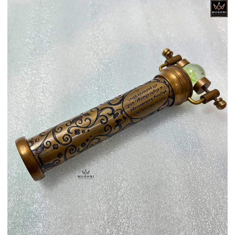 May include: A vintage brass kaleidoscope with an ornate floral design and the text "Life is like me ever a shifting kaleidoscope, a slight change, and all patterns alter." The kaleidoscope has a green glass lens.