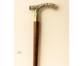 May include: A wooden walking cane with a brass handle. The handle is intricately carved with a floral design. The cane's shaft is a dark brown color, and the handle is a gold color. The cane has a brass ring near the bottom.