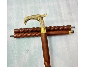 May include: A wooden walking cane with a brass handle and accents. The handle is curved and features an ornate floral design. The shaft has a twisted pattern. The cane is brown and gold.