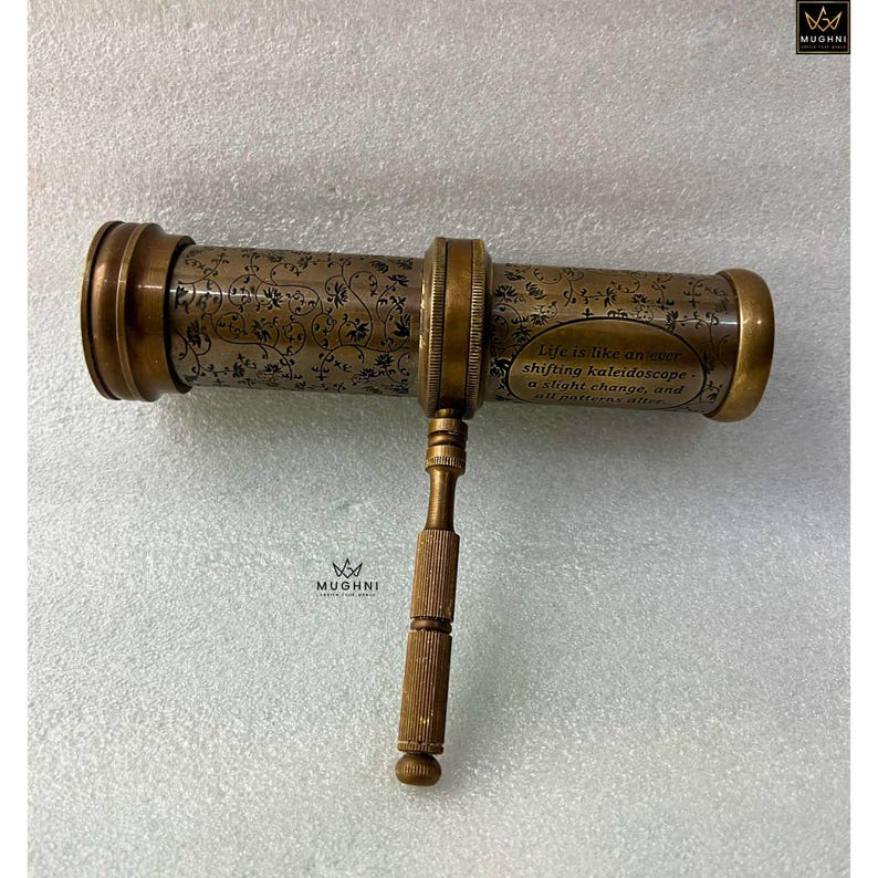 May include: Antique brass kaleidoscope with floral engravings and the text "Life is like an ever shifting kaleidoscope..." The vintage toy features a handle and decorative detailing. A classic optical instrument.