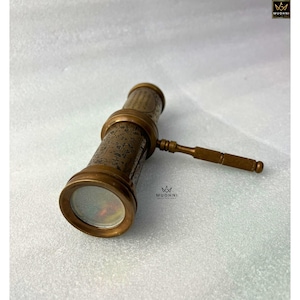 May include: A vintage brass telescope with intricate floral engravings. The telescope features a handle and lens, showcasing a classic design. The image is set against a neutral background, highlighting the antique aesthetic.