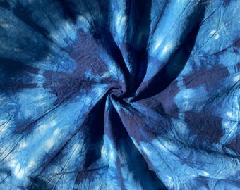 May include: Blue and white tie-dye fabric with a swirling pattern. The fabric is soft and textured, with a slightly wrinkled appearance.