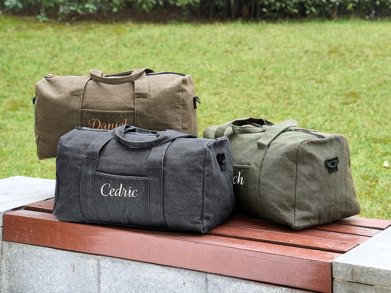 May include: Three canvas duffel bags in different colors. The bags have personalized names embroidered on them: Cedric, Daniel, and Rich.