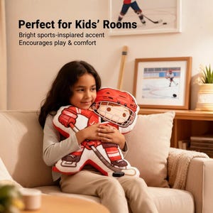 May include: A child is holding a hockey-themed pillow. The pillow is shaped like a hockey player in a red uniform and helmet, holding a hockey stick. The text "Perfect for Kids' Rooms" is visible in the image.