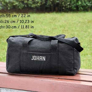 May include: Black canvas duffel bag with a white embroidered name "JOHAN". The bag measures 22 inches long, 10.23 inches wide, and 11.81 inches high.