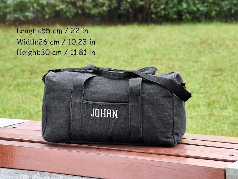 May include: Black canvas duffel bag with a white embroidered name "JOHAN". The bag measures 22 inches long, 10.23 inches wide, and 11.81 inches high.