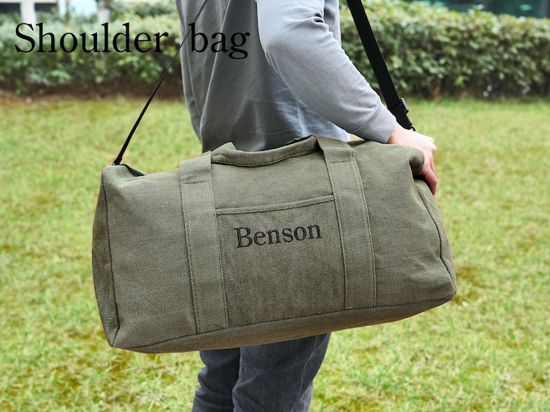 May include: A green canvas duffel bag with a black shoulder strap. The bag has a pocket on the front with the name "Benson" embroidered in black.