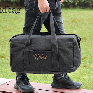 May include: A black canvas duffel bag with a zipper closure and a top handle. The bag has a pocket on the front with the name "Haley" embroidered in orange thread.