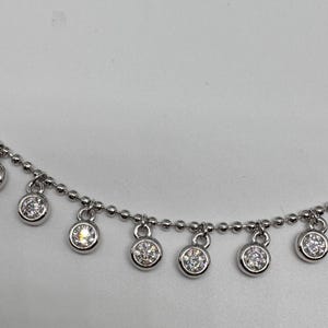May include: A silver chain necklace with small round dangling charms set with clear cubic zirconia stones.