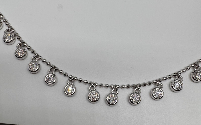 May include: A silver chain necklace with small round dangling charms set with clear cubic zirconia stones.