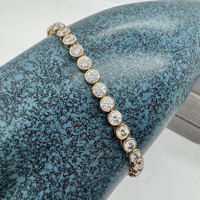 A gold tennis bracelet with round bezel set diamonds