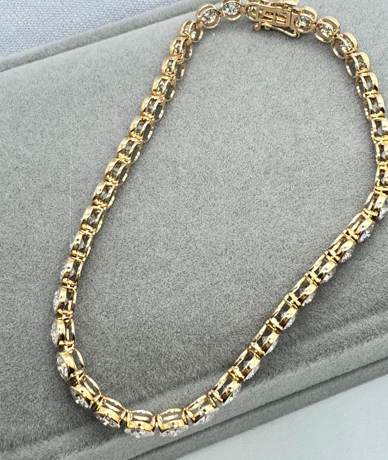 Close up side view of a gold tennis bracelet with round clear Moissanite stones