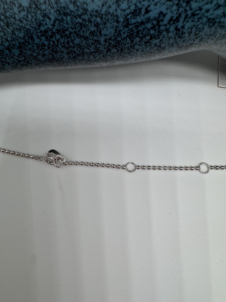May include: A silver chain necklace with a heart-shaped clasp and two circular links.