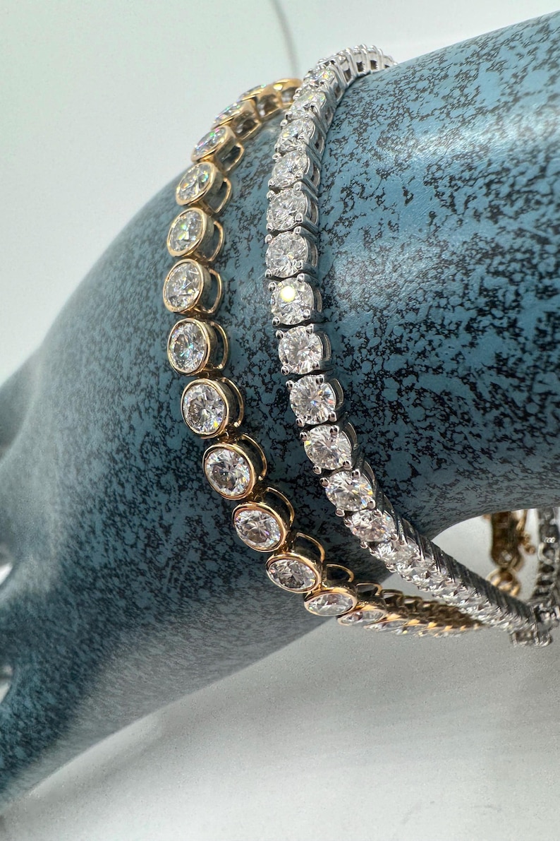 Two diamond tennis bracelets, one in yellow gold and one in white gold. Both bracelets feature round brilliant cut diamonds set in a pave setting.