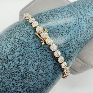 A gold tennis bracelet with round white stones