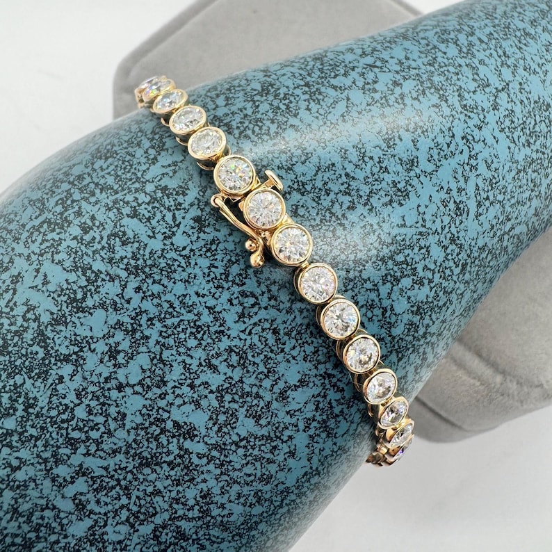 A gold tennis bracelet with round white stones