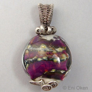 May include: A silver wire wrapped pendant featuring a round, multi-coloured glass bead. The bead has swirls of purple, white, and brown with gold flecks. The pendant is attached to a silver wire bail.
