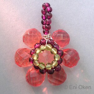 May include: A pink flower pendant made with faceted pink glass beads, green glass beads, and purple glass beads. The pendant is strung on wire and has a purple glass bead chain.