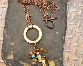 Pendant Necklace with a collection of unique beads hanging from a ivory color circle