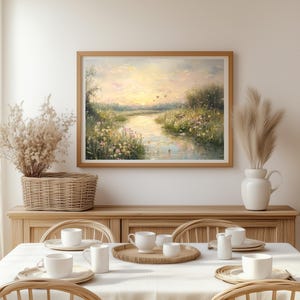 May include: A framed painting of a landscape with a river winding through a field of wildflowers. The sky is a soft blue with a hint of pink and yellow. The painting is in a wooden frame and is hanging on a white wall.