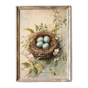 Puede incluir: Una pintura enmarcada de un nido de pájaro con cuatro huevos azules, rodeados de delicadas flores blancas y hojas verdes sobre un fondo azul claro.