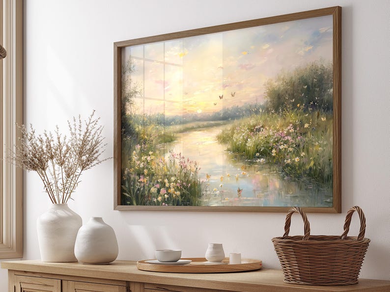 May include: A framed painting of a peaceful river scene with a sunset in the background. The river is surrounded by lush green grass and wildflowers. Butterflies fly in the sky above the river.