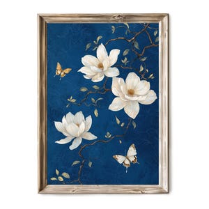 May include: A framed print of white magnolia flowers with delicate branches and two butterflies on a deep blue background.