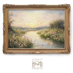 May include: A framed painting of a peaceful landscape with a river winding through a field of wildflowers. The sky is a soft blue with hints of pink and orange, suggesting a sunset. The painting is in a gold frame with ornate details.