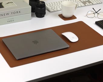 May include: A brown leather desk mat with a laptop computer, a white mouse, and a pair of eyeglasses on a white desk.