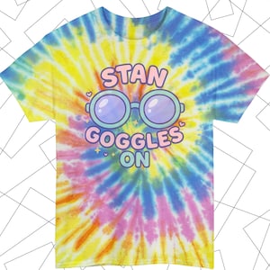 May include: A tie-dye t-shirt with a vibrant swirl of yellow, blue, pink, and orange. The shirt features the text "STAN GOGGLES ON" above a pair of cartoon glasses. The design includes hearts and stars.