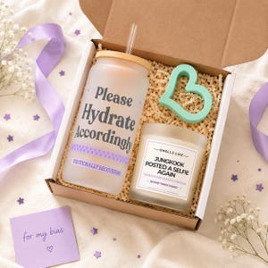 May include: A gift box containing a frosted glass tumbler with a bamboo lid and straw, featuring the text Please Hydrate Accordingly and Emotionally Recovering, a mint green heart-shaped object, and a candle labeled Smells Like Jungkook Posted A Selfie Again.