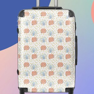 May include: A patterned suitcase featuring the words "AQUA RIUS" in coral and blue, with aquatic plant illustrations and yellow bubbles on a white background. The suitcase has a black handle and wheels. The case is designed for travel.