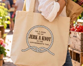 May include: A beige canvas tote bag featuring a black graphic of a rope tied into a circle. Inside the rope circle, the text reads: I'M A FIXIN TO GO JERK A KNOT IN THE GOVERNMENT'S TAIL. The bag has two shoulder straps and a rectangular shape.