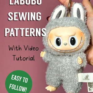 May include: A plush, gray Labubu character with large black eyes, a smiling mouth, and small arms and feet. The image includes text that reads "LABUBU SEWING PATTERNS With Video Tutorial EASY TO FOLLOW!"