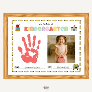 Puede incluir: Una impresión enmarcada para el primer día de guardería de un niño. La impresión presenta el texto "my first day of KINDERGARTEN", una huella de mano roja, una foto de un niño sonriente, el nombre "Emma Collins" y la fecha "17/09/2025".