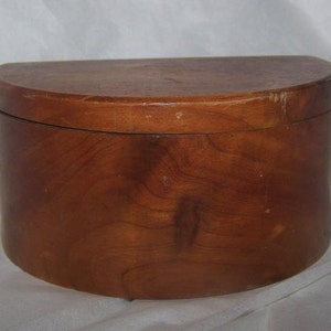 May include: A half-round wooden box with a lid. The box is made of light brown wood with a smooth finish.