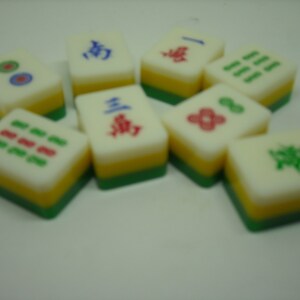 May include: A set of nine colorful mahjong tiles with Chinese characters and symbols. The tiles are arranged in a semi-circle on a white surface.
